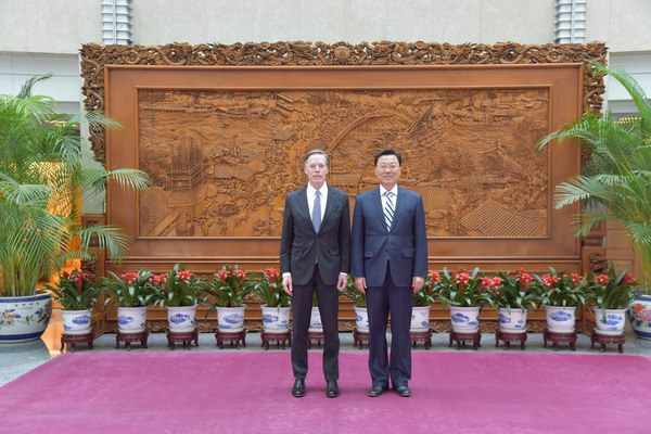 Two men in suits standing in front of a wall with flowers

Description automatically generated with low confidence